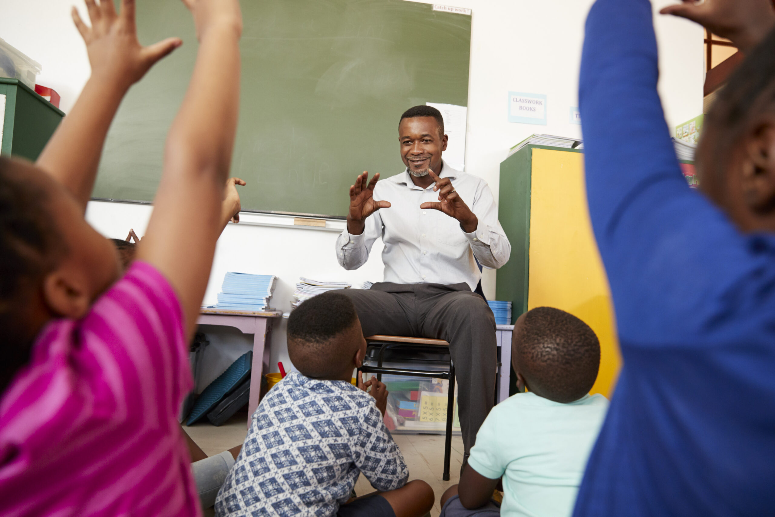 Elementary school kids sitting on floor listening a teacher