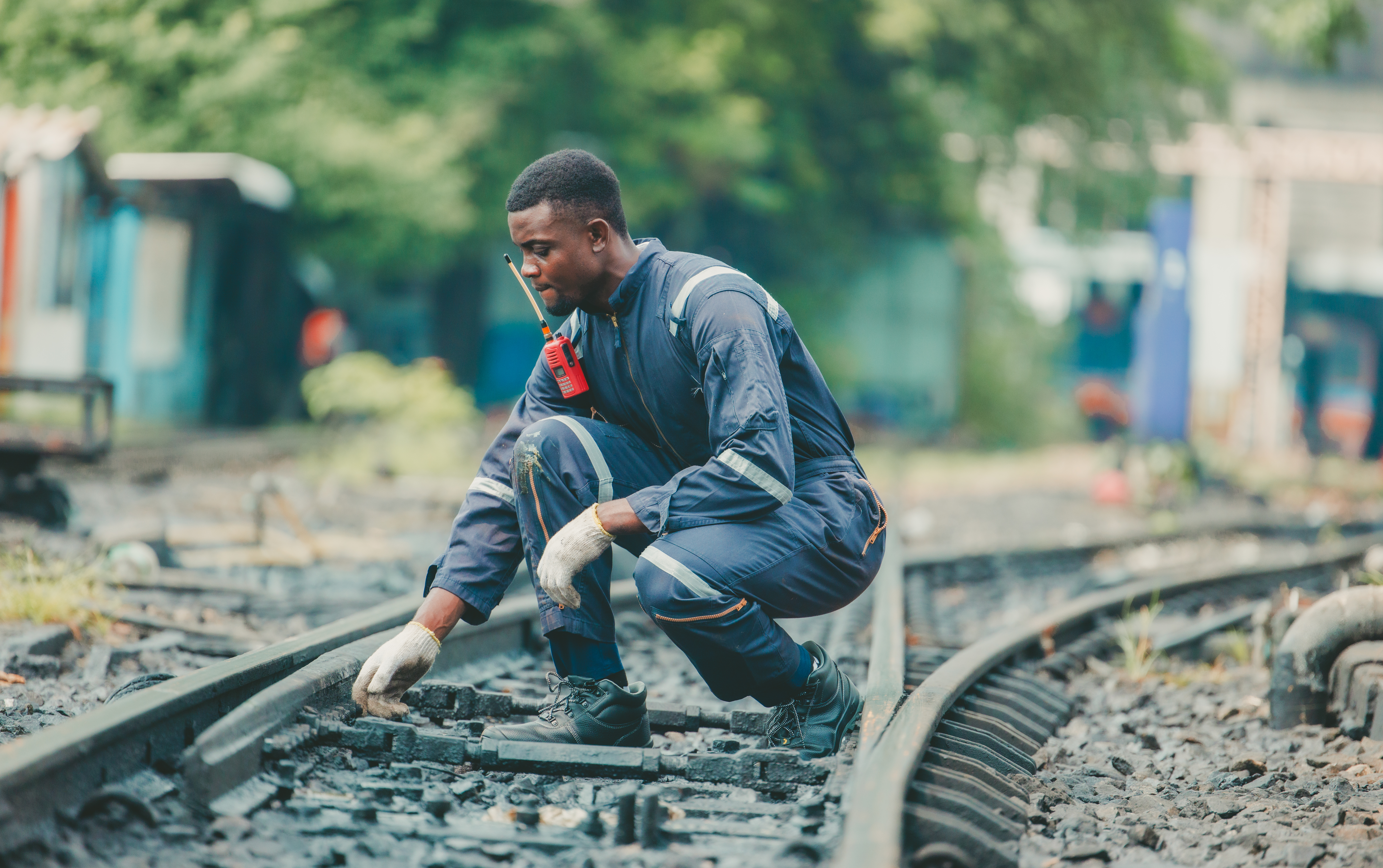 The locomotive maintenance engineer, dressed in safety gear, inspects the railway track for signs of wear and proper alignment. Focus on detail and precision. Ensuring it meets all safety standards.