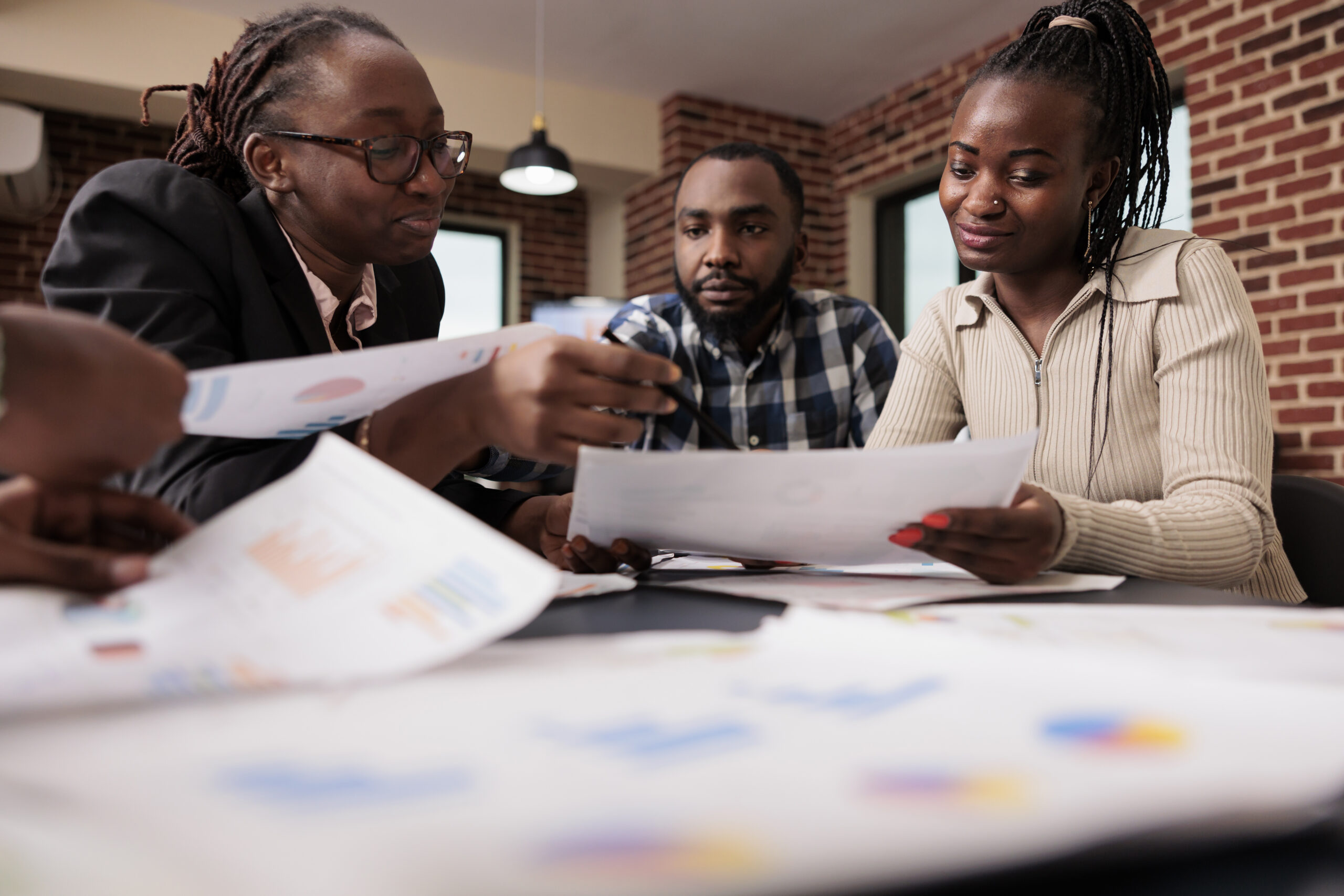 Team of coworkers analyzing business files in startup office, meeting to do teamwork collaboration on corporate presentation. Working with papers and data information to plan company report.
